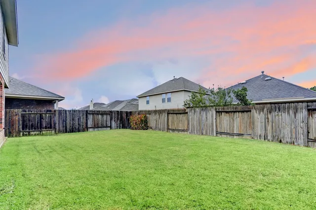 a view of a house with a yard and wooden fence
