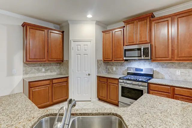 a kitchen with stainless steel appliances granite countertop a stove a sink and a microwave