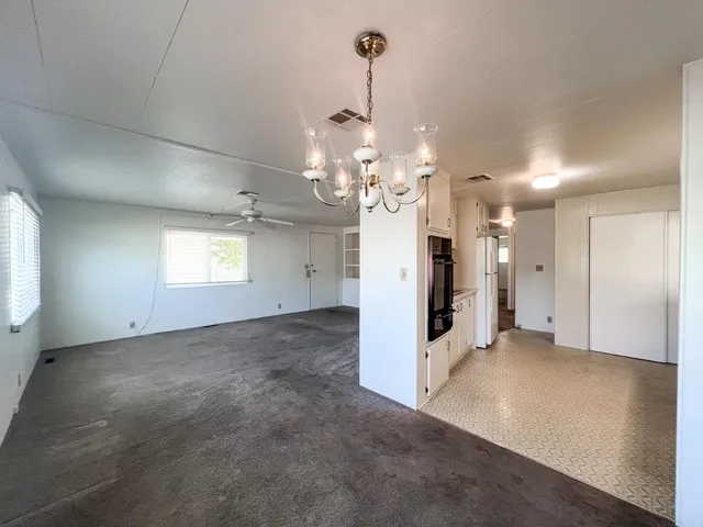 an empty room with chandelier and windows