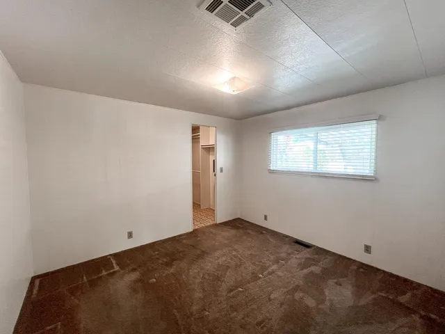 an empty room with a chandelier fan and windows