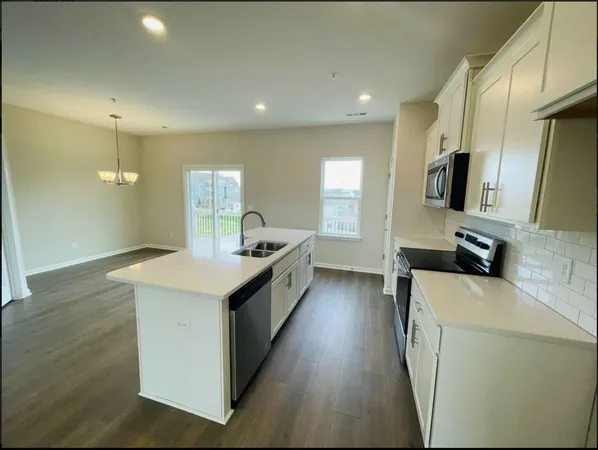 a large kitchen with stainless steel appliances a large counter top a stove a sink and a refrigerator