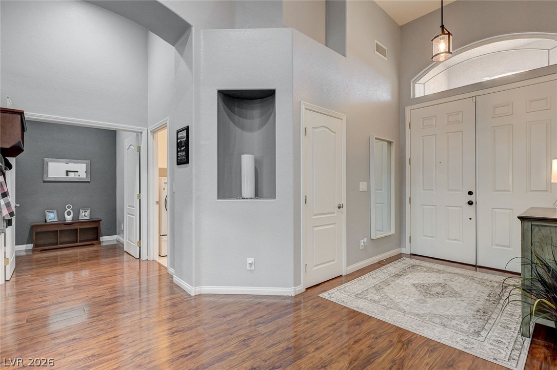 1604 Cattle Ranch Place Henderson, NV 89002 - Photo 11 of 99 Enter into a grand foyer featuring rich wood-look flooring and an arched transom window above the double entry doors.