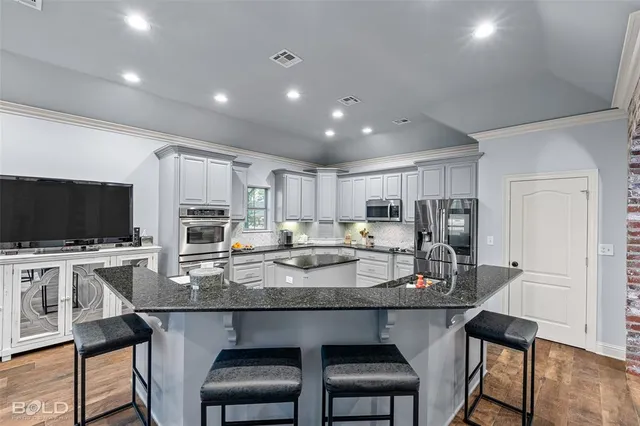 a kitchen with kitchen island granite countertop a table chairs microwave and sink