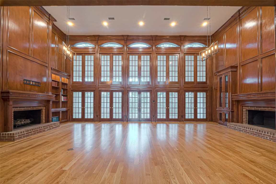 27165 Kestrel Trail Magnolia, TX 77354 - Photo 7 of 50 This spacious living room features high ceilings, elegant wood paneling, and large multi-pane windows that flood the area with natural light. It includes two brick fireplaces and built-in shelving, creating a warm and inviting atmosphere.