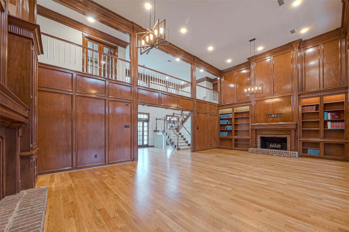 27165 Kestrel Trail Magnolia, TX 77354 - Photo 9 of 50 This spacious room features elegant wood paneling, a cozy brick fireplace, built-in bookshelves, and a lofted area with a staircase. High ceilings and ample lighting enhance the warmth and grandeur. Perfect for a luxurious and inviting living space.