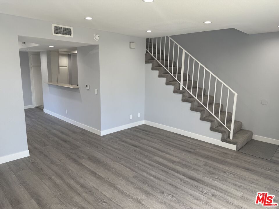 7639 Kester Avenue, Unit 1 Van Nuys, CA 91405 - Photo 1 of 21 a view of staircase with white walls and wooden floor