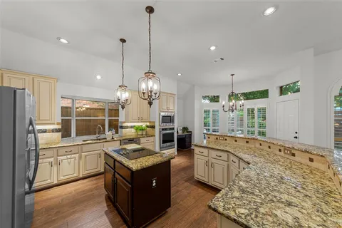 a large kitchen with kitchen island a stove a sink a center island and furniture