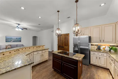 a kitchen with stainless steel appliances granite countertop a stove a sink dishwasher a refrigerator and a wooden floor