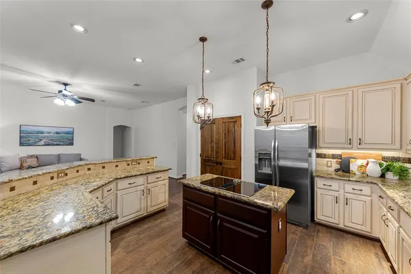 a kitchen with stainless steel appliances granite countertop a stove a sink dishwasher a refrigerator and a wooden floor