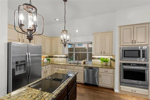 a kitchen with stainless steel appliances granite countertop a stove refrigerator and microwave