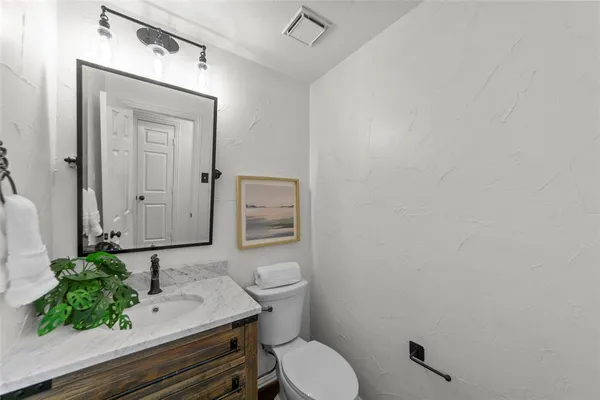 a bathroom with a granite countertop toilet sink and mirror