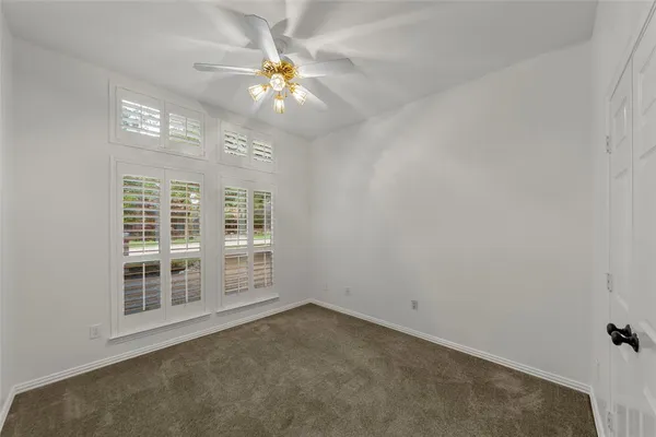 a view of an empty room with a chandelier fan and a large window