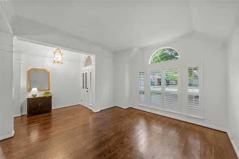 a view of empty room with wooden floor and fan