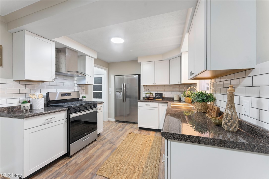 620 Edison Street Struthers, OH 44471 - Photo 8 of 23 Kitchen featuring light hardwood / wood-style flooring, backsplash, white cabinetry, stainless steel appliances, and wall chimney range hood