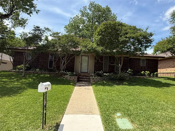 a front view of a house with garden and a yard
