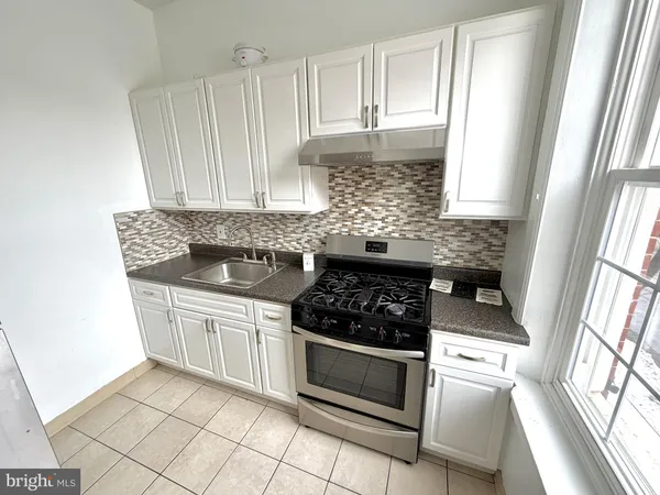 a kitchen with white cabinets a sink and a stove