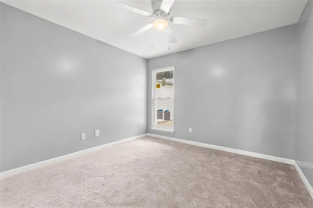 an empty room with a chandelier fan and closet area