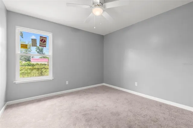 a view of an empty room and chandelier fan