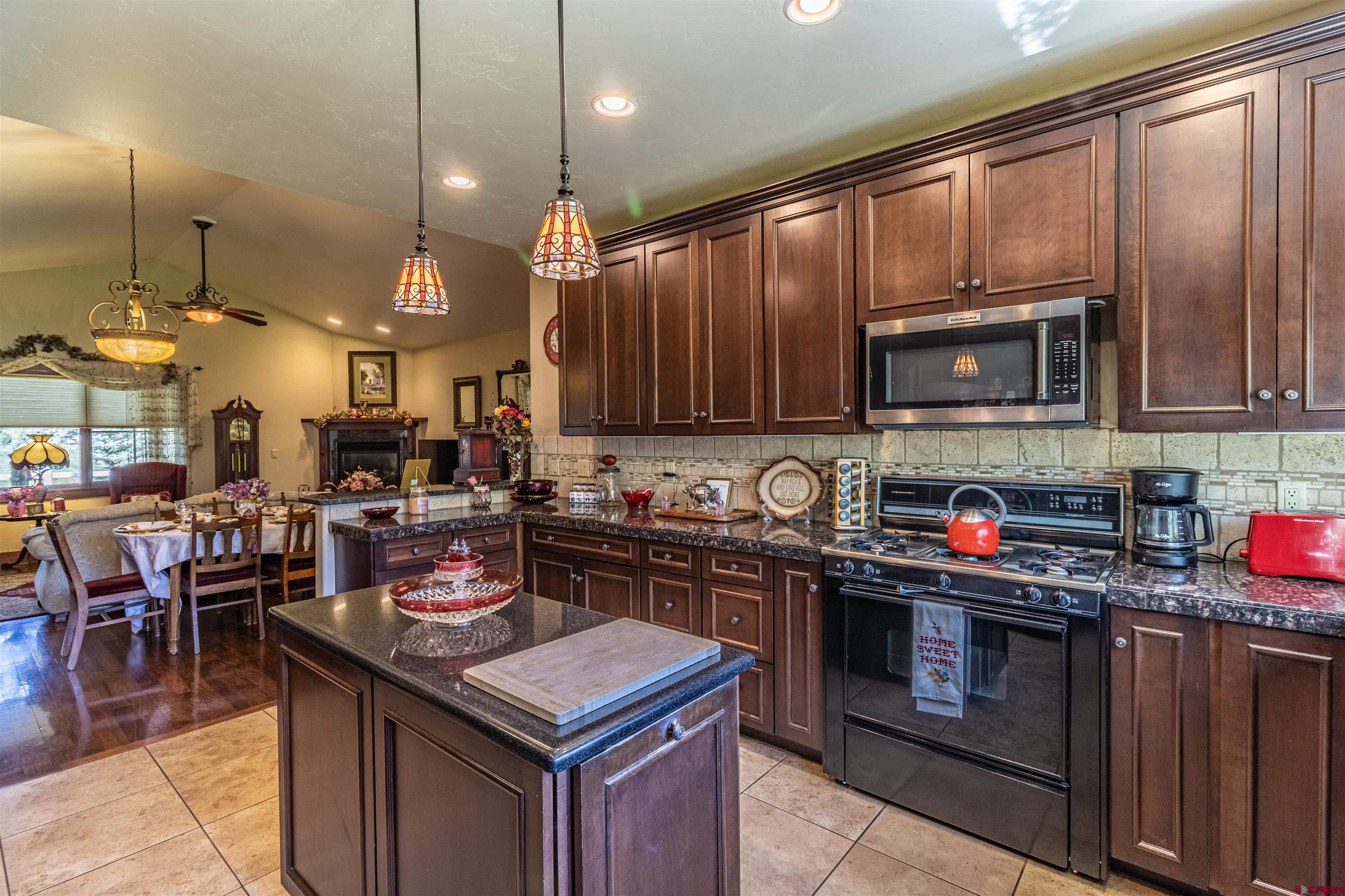 1167 North Dalton Ranch Road Durango, CO 81301 - Photo 12 of 45 a kitchen with kitchen island granite countertop a stove top oven a sink dishwasher a dining table and chairs with wooden floor