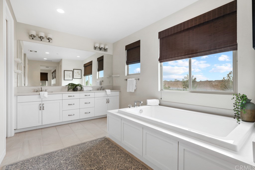 279 Barnes Road Tustin, CA 92782 - Photo 21 of 32 a bathroom with a sink a large mirror and a bathtub next to a window