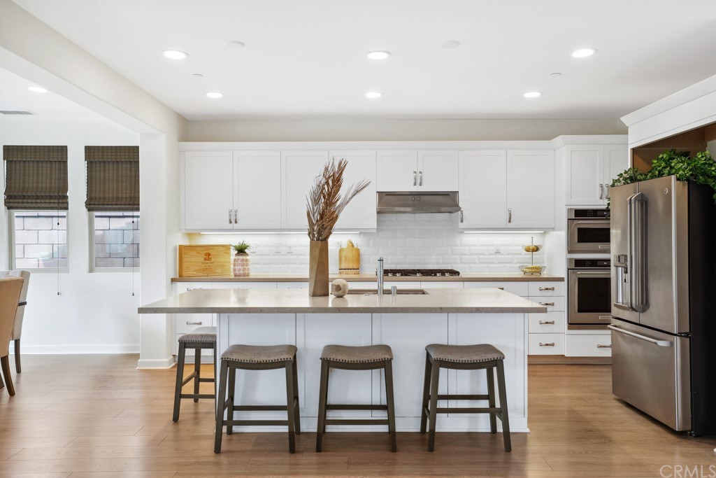 279 Barnes Road Tustin, CA 92782 - Photo 9 of 32 a kitchen with stainless steel appliances a table chairs refrigerator and microwave