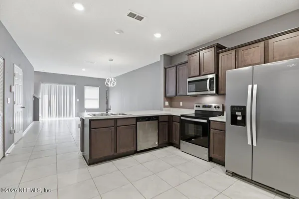 a large kitchen with granite countertop a refrigerator and a stove top oven