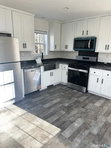 a kitchen with granite countertop a stove a sink and a refrigerator