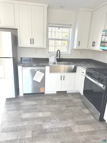 a kitchen with granite countertop white cabinets and white appliances
