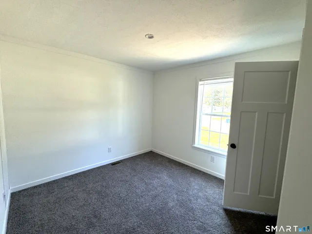 an empty room with a window and a kitchen view