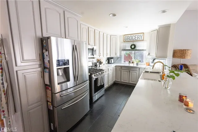 a kitchen with stainless steel appliances a refrigerator a sink a stove and white cabinets
