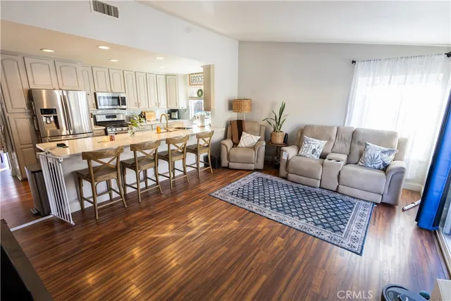 a living room with stainless steel appliances furniture and a wooden floor