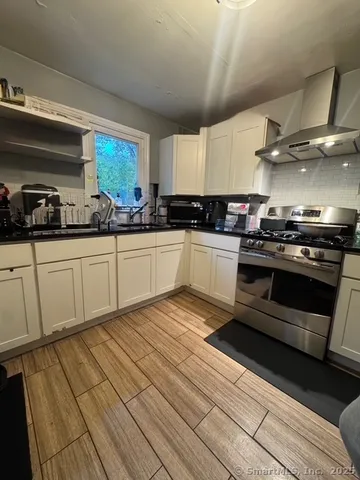 a kitchen with stainless steel appliances a stove a sink and white cabinets
