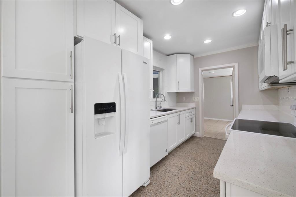 2331 West Oak Street Kissimmee, FL 34741 - Photo 4 of 34 a large white kitchen with a refrigerator a sink and a stove top oven