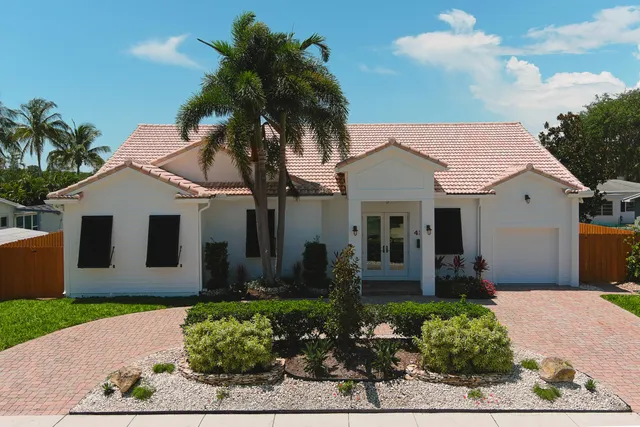 a front view of a house with a yard and potted plants