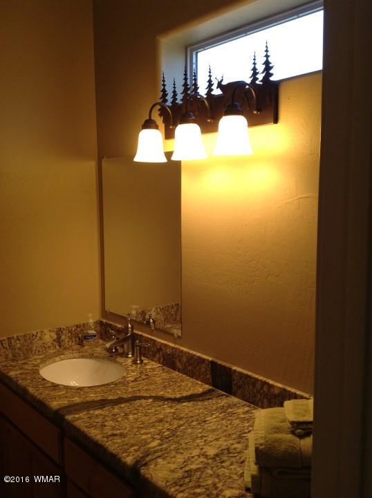 2972 Lodgepole Road Overgaard, AZ 85933 - Photo 31 of 41 a bathroom with a granite countertop sink and a mirror