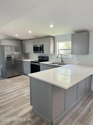 a large kitchen with kitchen island a sink stainless steel appliances and cabinets
