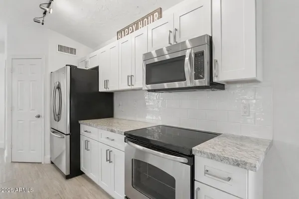 a large kitchen with granite countertop a sink counter top space appliances and cabinets