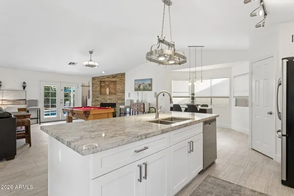 a kitchen with granite countertop stainless steel appliances a refrigerator a stove a sink cabinets and wooden floor