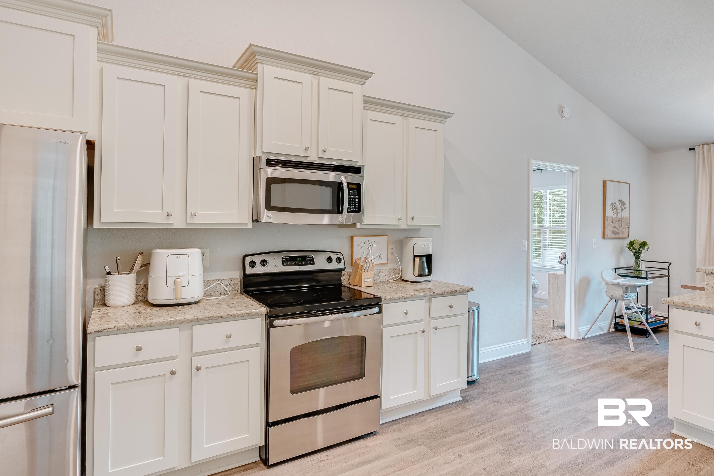 2215 Fernwood Loop West Semmes, AL 36575 - Photo 12 of 40 Kitchen featuring white cabinetry, stainless steel appliances, granite-finish countertops, wood-finish flooring, and a vaulted ceiling