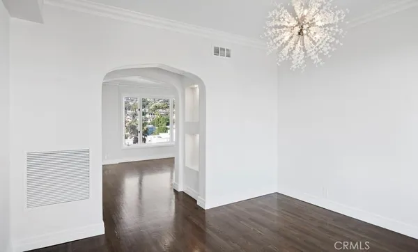 an empty room with wooden floor windows and entrance