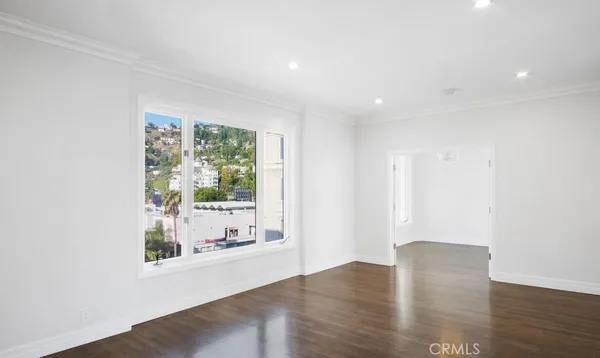 a view of an empty room with wooden floor and a window