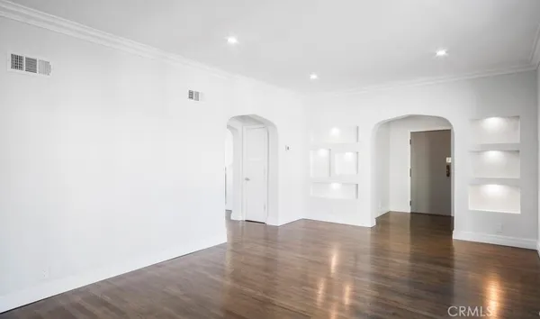 a view of an empty room with wooden floor and a ceiling fan
