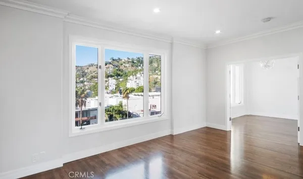 a view of an empty room with wooden floor and a window
