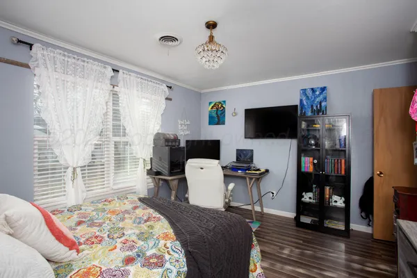 a bedroom with a bed a computer on desk and a chair