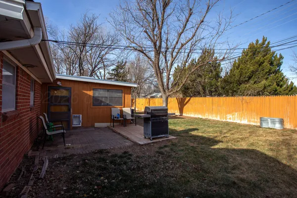 a view of a backyard with table and chairs and a barbeque