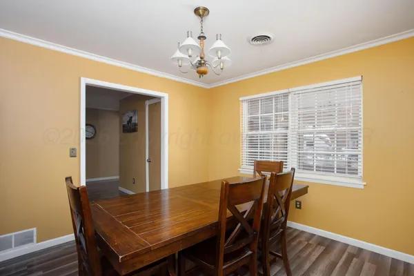 a dining room with wooden floor a chandelier a wooden table and chairs