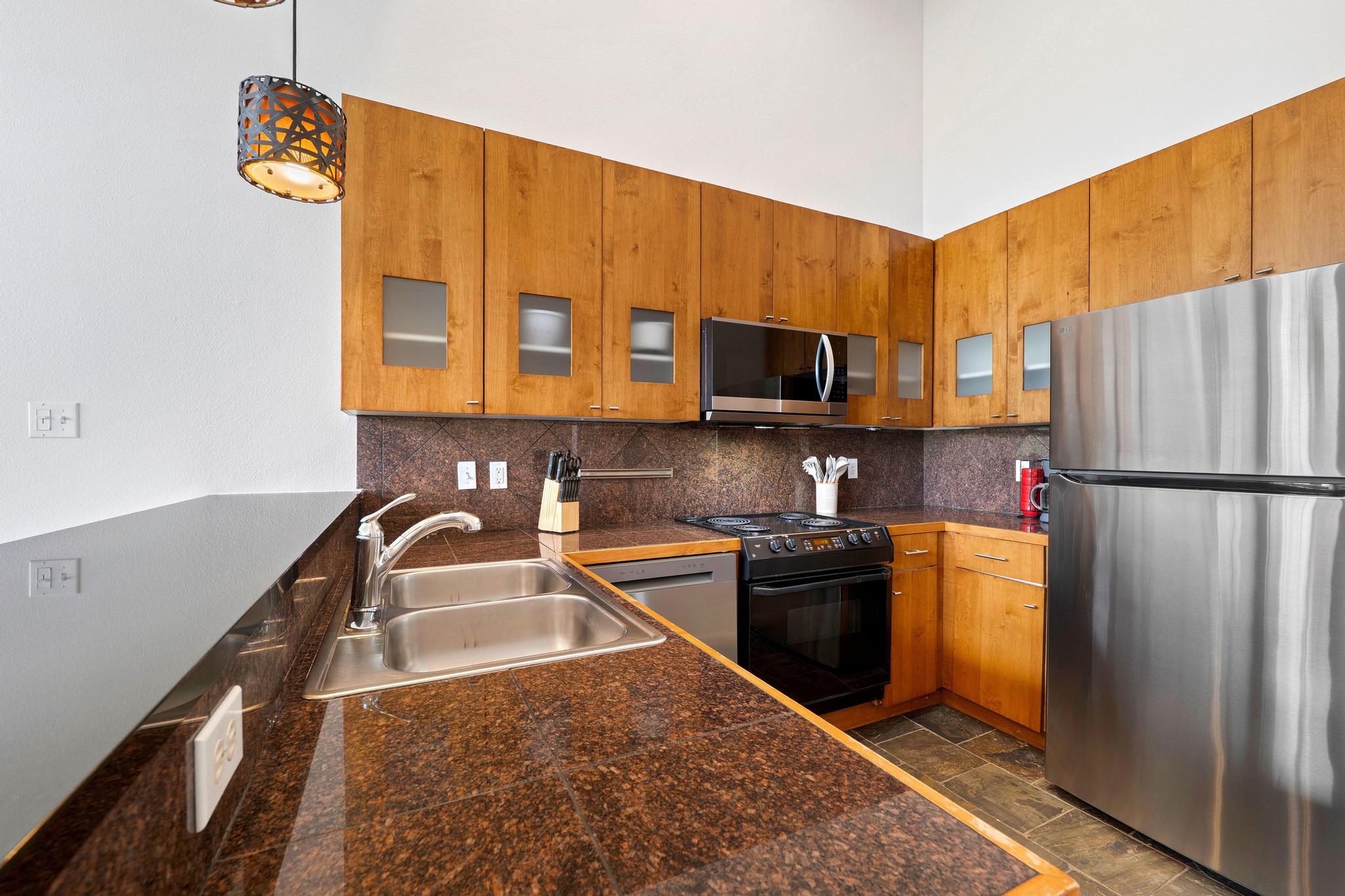 2918 Ranch Road 620, Unit J162 Austin, TX 78734 - Photo 8 of 26 Kitchen featuring rich brown countertops, light wood-finish cabinetry with frosted glass accents, and a stainless steel refrigerator
