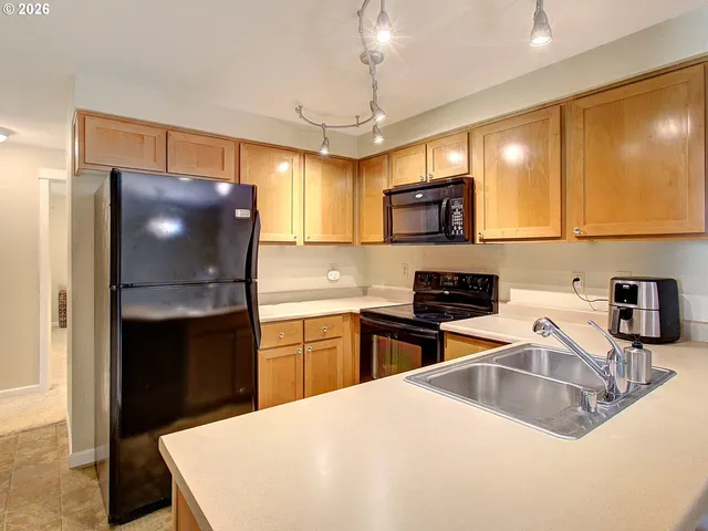 a kitchen with granite countertop a refrigerator a sink a stove a microwave a counter top and cabinets