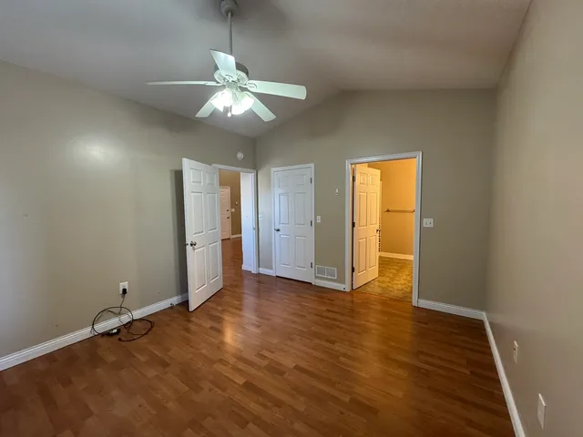 an empty room with wooden floor closet and windows