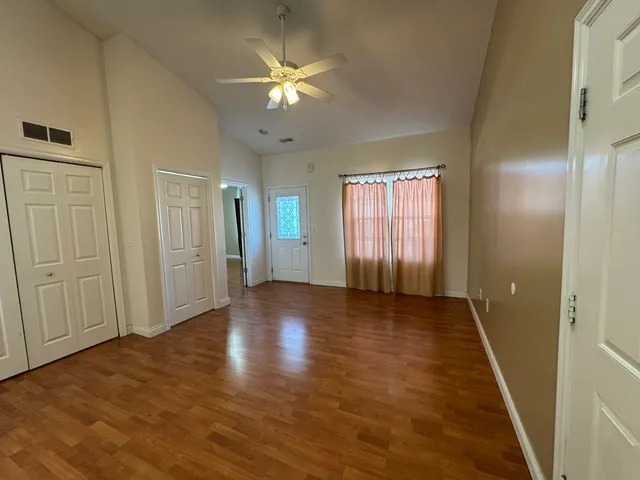 a view of an empty room with window and wooden floor